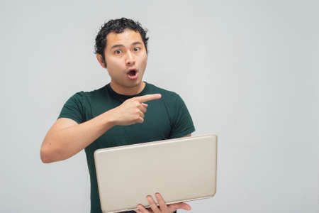 Young hispanic mexican with green shirt and laptopの写真素材