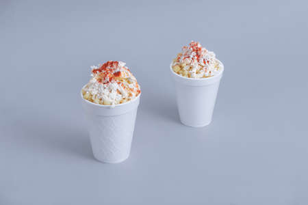 Mexican snack, two trolley, prepared esquite, corn in a cup, with chili powder on orange background, no peopleの写真素材