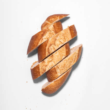 Freshly baked artisan Mexican bread cut into slices, frensh bread roll, top view on white...