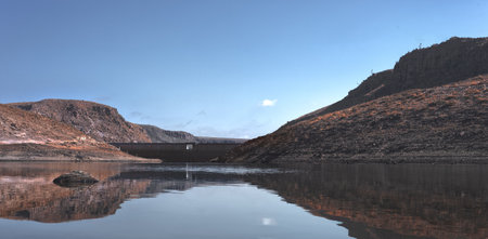lake view of a dam among the plain of an arid climate with blue sky and few clouds, without people and animals, place of mountain hike, great viewの写真素材