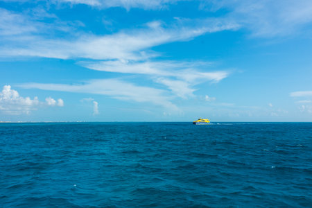 cancun cancun, 20 08 23, Yellow ferry crosses Cancun's blue sea on a day of slightly cloudy skies and calm watersのeditorial素材