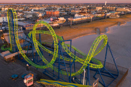 Big, bright green roller coaster on a beach.のeditorial素材