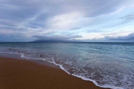 Beach, sand, waves, and sunrise clouds on Mauiの写真素材