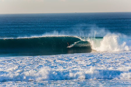 Surfing rider on long blue wave wall under the pitching lipのeditorial素材
