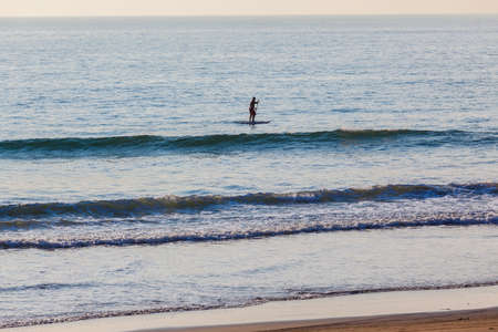 Surfing sup rider along in small wave ocean surfの写真素材