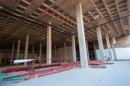 Construction building with red high pressure fire water pipes being installed in roofing structures
