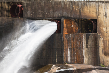 Dam sleuth gates water flowing down valley river の写真素材