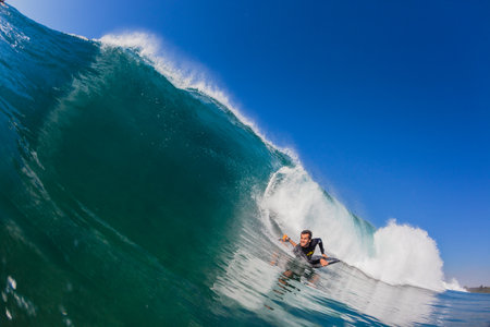 Body-Boarding rider rides blue upright wave, close water photography of action
