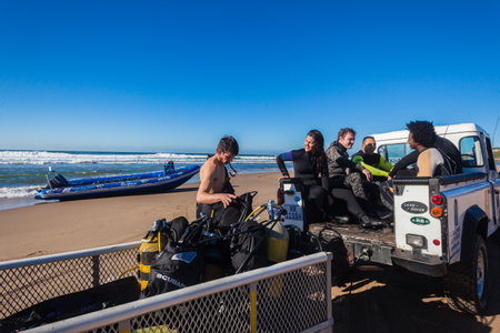 Scuba divers finished diving for the day sitting in 4x4 vehicle with bottle rigs in trailer leaving the beachのeditorial素材