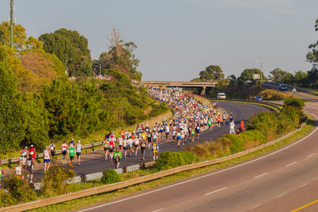 Marathon ultra distance race hundreds of runners in morning sun light on old main road highwayのeditorial素材