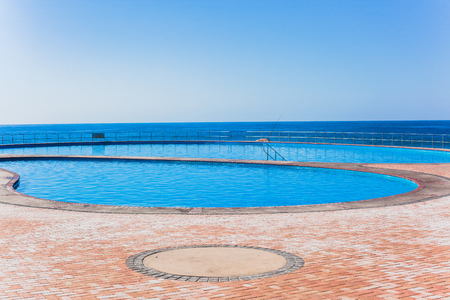 Swimming pools outdoor next to ocean sea side with blue horizon