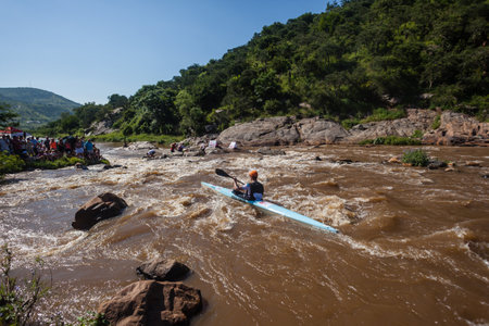 Canoe race marathon with athlete paddling on fast river rapid waters though rural thick vegetation landscapeのeditorial素材