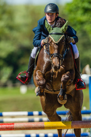 Horse male rider jumping mid flight over gate at regional state equestrian competition のeditorial素材