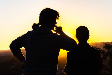 Mother daughter affections relationship love discipline contrasts silhouetted in dusk sunset skyの写真素材