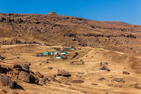 Rugged mountain terrain with distant tribal home alongside rocky landscapeの写真素材