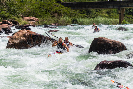Paddlers break canoe around large river water rapid rock in dusi canoe race action drama at Inanda valley with teams going through dangerous rushing river watersのeditorial素材