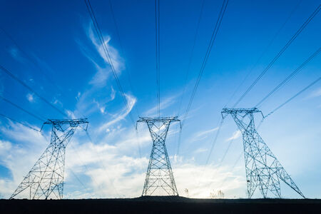 Electrical tower pylons cable power-lines silhouetted in afternoon sunset blue skyの写真素材