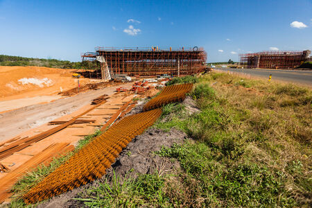 Building bridge construction site set over road against a clear blue sky with fluffy white cloudsの写真素材