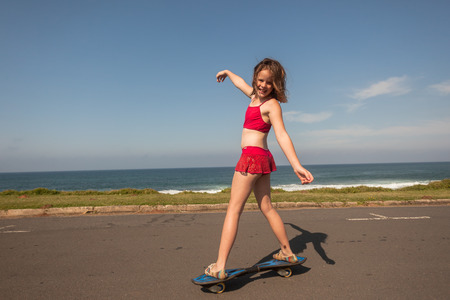 Young girl skateboarding on beach road during holidaysの写真素材