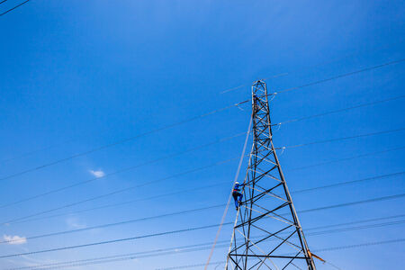 Steel Electrical power pylons with maintenance teams up high on cable connectors の写真素材