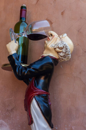 Butler doll drinking glass of wine and holding bottleの写真素材