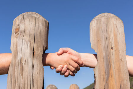 Handshake abstract form through wood poles for distant agreement barrierの写真素材