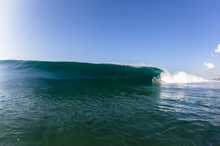 Blue ocean wave wall of sea water upright round crashing breaking onto reef beach shallowsの写真素材