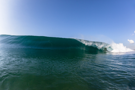 Blue ocean wave wall of sea water upright round crashing breaking onto reef beach shallowsの写真素材