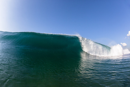Blue ocean wave wall of sea water upright round crashing breaking onto reef beach shallowsの写真素材
