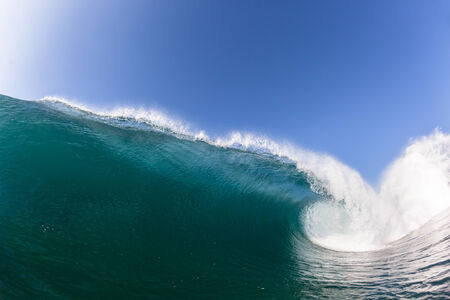 Blue ocean wave wall of sea water upright round crashing breaking onto reef beach shallowsの写真素材