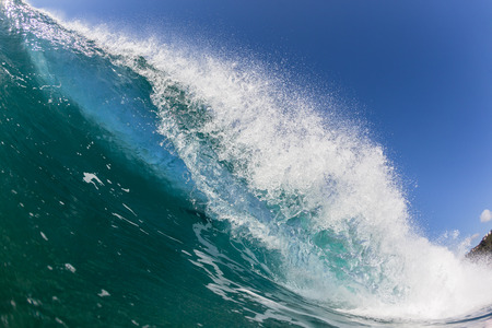 Blue ocean wave wall of sea water upright round crashing breaking onto reef beach shallowsの写真素材