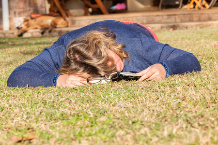 Woman at home relaxing outdoors reading book sleeping nap in afternoon sunlightの写真素材