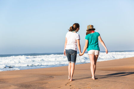 Teenager girls social relaxing walk at beach with ocean waves early morning outdoors holidayの写真素材