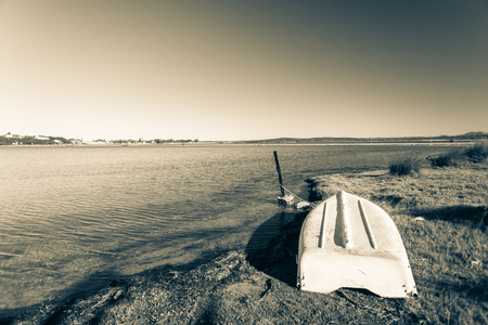 Abandoned boat upside down next to river beach lagoon in sepia black white vintage toneの写真素材