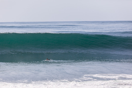 Surfer paddles hard to escape beating from crashing ocean waveの写真素材