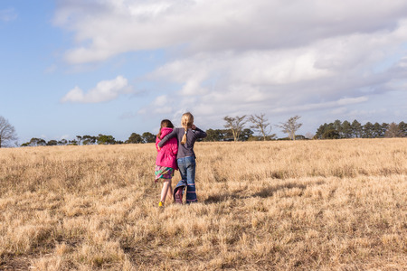 Young girl caring assists friend back to camping site in rural countrysideの写真素材