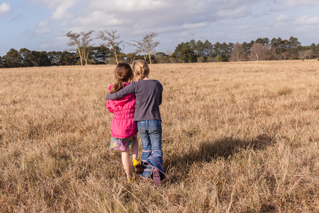 Young girl caring assists friend back to camping site in rural countrysideの写真素材