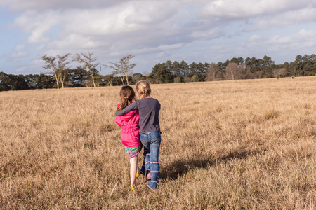 Young girl caring assists friend back to camping site in rural countrysideの写真素材