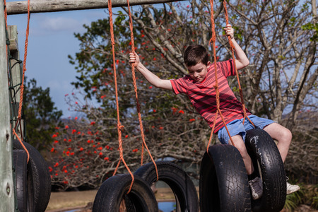 Young boy climbing playground ropes tyre s swing apparatusの写真素材