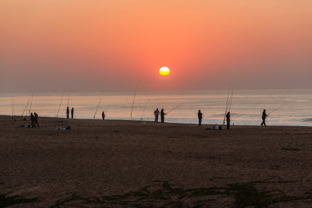 Dawn beach fishermen silhouetted fishing landscape at sunrise over the sea ocean watersのeditorial素材