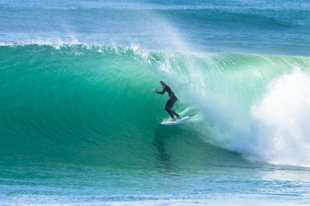 Surfing surfer rides inside hollow tubing ocean wave Durban South Africaのeditorial素材
