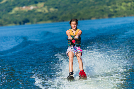 Teen girl watersking on scenic dam landscapeの写真素材