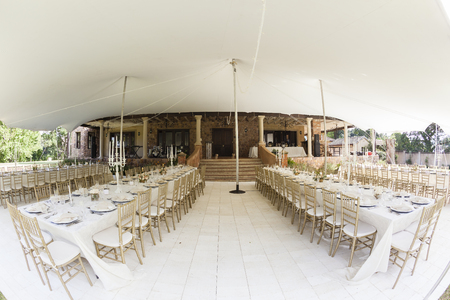 Tent decor dining tables chairs cutlery outdoors party celebration dinner at private homeの写真素材