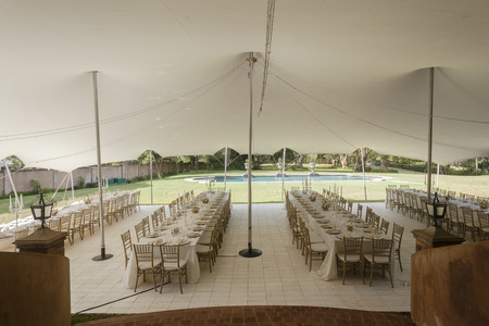 Tent decor dining tables chairs cutlery outdoors party celebration dinner at private homeの写真素材