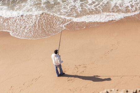 Fisherman on beach sands water shoreline unidentified.の写真素材