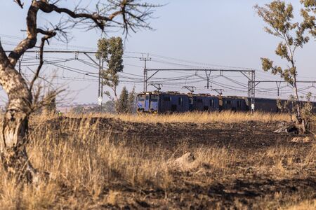 Railway train coaches travel through dry season rural landscapeの写真素材
