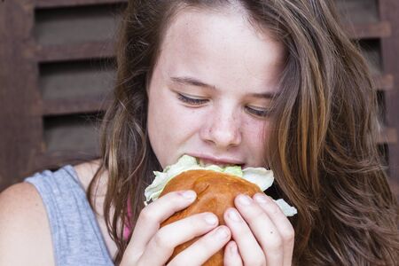 Teen girl eating lunch fresh bread roll sandwichの写真素材