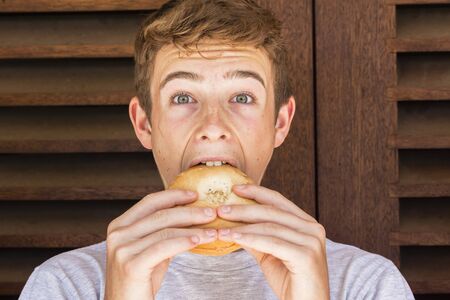 Teen boy eating lunch fresh bread roll sandwich