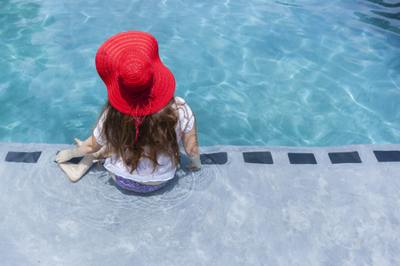 Teenager girl red hat summer swimming pool recreationの写真素材