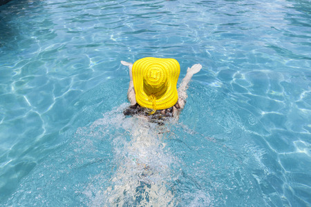 Girl swimming with yellow hat  pool summerの写真素材